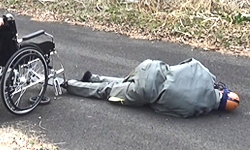 Scene from the video: wheelchair user assisted by attendant falling down after the front wheel was broken during use